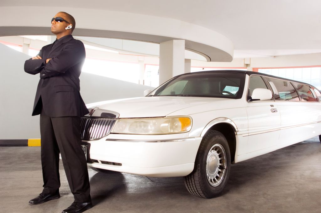 A chauffer standing by a stretch limousine